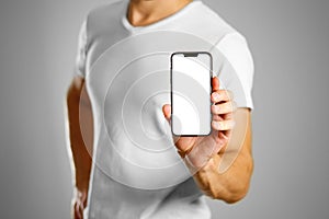 A man holding a black smartphone with a white blank screen. Smartphone with large screen. Close up. Isolated background