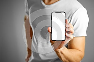 A man holding a black smartphone with a white blank screen. Smartphone with large screen. Close up. Isolated background