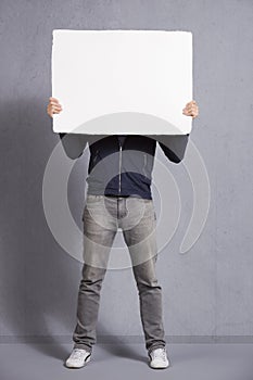 Man holding blank panel covering his face.