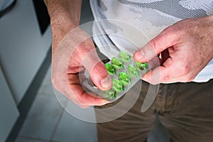 Man holding a blister pack of green capsules. Medicine, health care concept