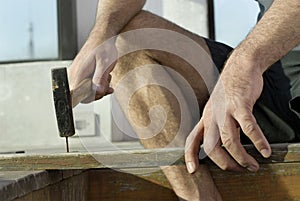 Man Holding Board while Hammering - Horizontal