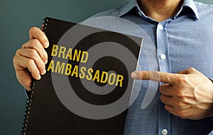 Man holding book with title Brand Ambassador. photo