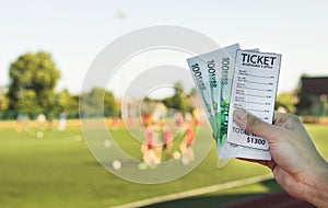 Man is holding a bookmaker`s ticket and money euros in the background of a stadium football game, close-up