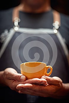 man holding with both hands orange cup of coffee. copy space