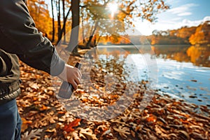 man holding a bottle found among autumn leaves, lake and trees in autumn colors