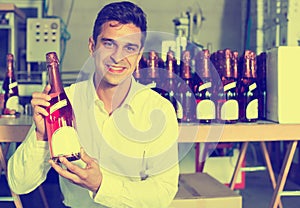 Man holding bottle of wine in wine factory