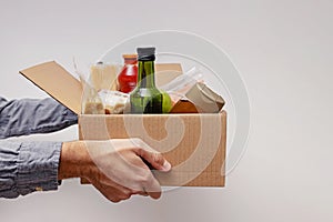 Man holding a box full on canned and packed foodstuff