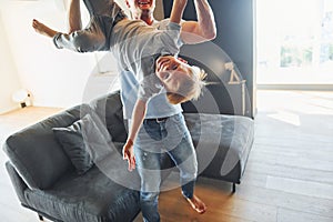 Man holding boy and having fun. Father and son is indoors at home together