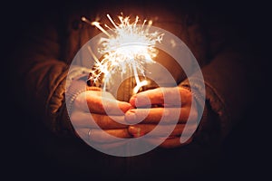 Man holding bright festive Christmas sparkler in hand, tinted ph