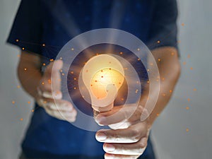 Man holding bright shining light bulb represents a new idea, thought, invention, innovation, solution, creativity, technology, and