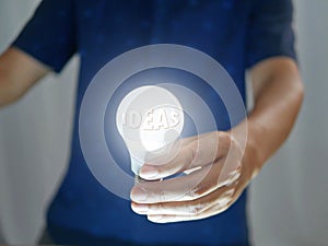 Man holding bright shining light bulb represents a new idea, thought, invention, innovation, solution, creativity, technology, and