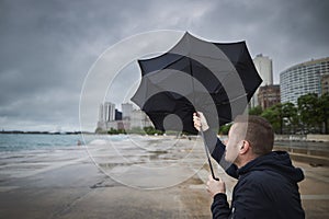 Man holding broken umbrella in strong wind