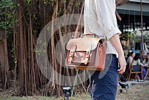 Man holding a brown leather bag