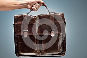 A man holding a brown leather travel bag photo