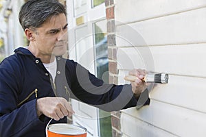 Man Holding Brush And Tin Painting Outside Of House photo