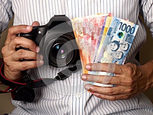 Man holding a camera and Philippine peso bills