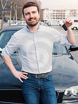 Man holding a car key next to his vehicle