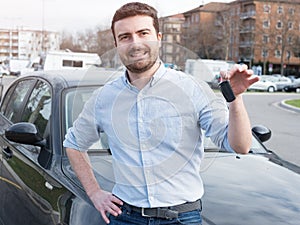 Man holding car key next to his vehicle