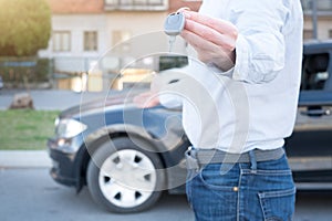 Man holding a car key next to his vehicle