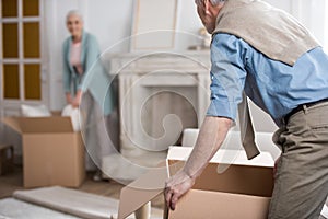 Man holding cardboard box and helping wife unpack things