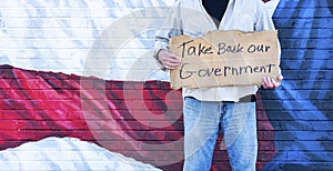 Man holding cardboard sign, Take Back Our Government, with American Flag,