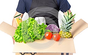 Man holding a carton box with lettuce, tomato and spaghetti, pineapple isolated on white