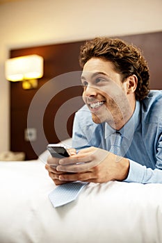 Man holding cellphone and lying on bed, relaxed