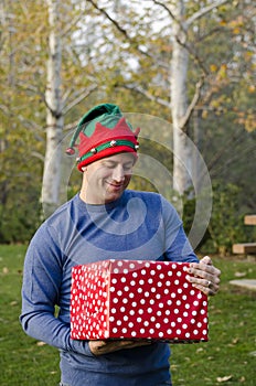 Man holding a Christmas present outside.