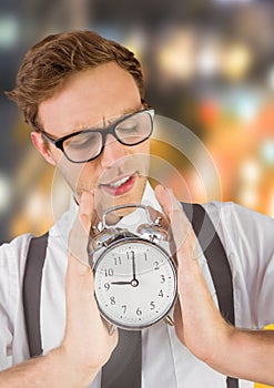 man holding clock in front of blurred colorful background