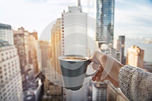 Man holding coffee cup in luxury penthouse apartments with view to New York City