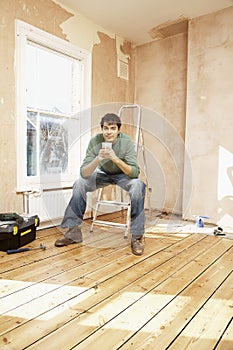 Man Holding Coffee Mug On Step Ladder In Unrenovated Room photo