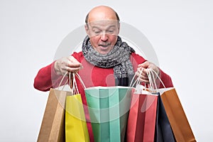Man holding colored shopping bag and looking with surprise inside.