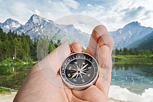 Man is holding compass in hand. Hiking and tourism concept. Mountains in background