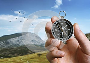 Man holding a compass over a landscape view