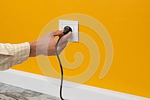 Man holding cord plugged into a electrical outlet