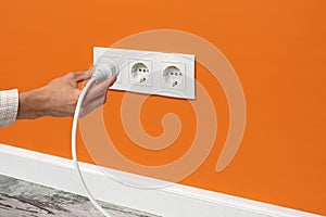 Man holding cord plugged into a electrical outlet
