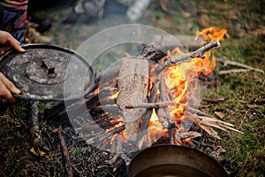 Man holding cover placing on the pan near the campfire