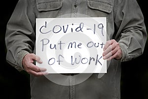 Man holding covid-19 put me out of work homemade sign