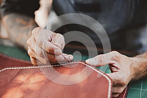 Man holding crafting tool and working. He is sewing hammer to make a wallet