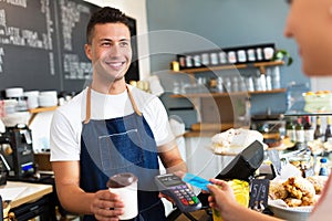 Man holding credit card reader at cafe