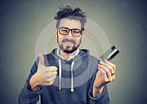 Man holding a credit card showing thumbs up