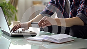 Man holding credit card, typing on laptop, paying for utilities, shopping online