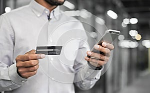 Man holding credit card and using smart phone. Businessman or entrepreneur working in office. Online shopping, internet banking