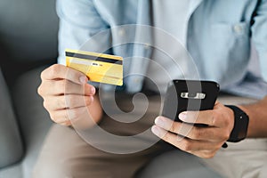 Man holding credit card and using smartphone for online shopping, internet banking, e-commerce, spending money, working from home