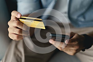 Man holding credit card and using smartphone for online shopping, internet banking, e-commerce, spending money, working from home