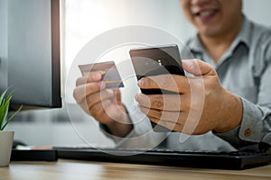 A Man holding credit card and using smartphone for payment online for purchase after order products via the internet. The concept