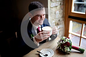 man, holding cup of cappuchino in the hands photo