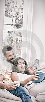 Man holding a cup of coffee while woman reading book