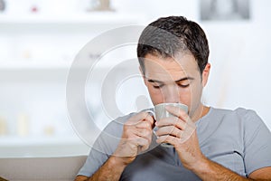 man holding cup sat on sofa