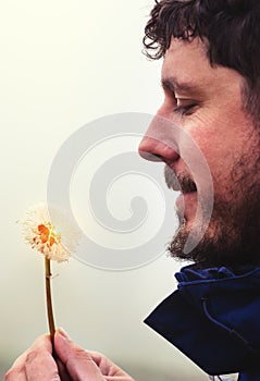 Man holding dandelion with water drops in the hands
